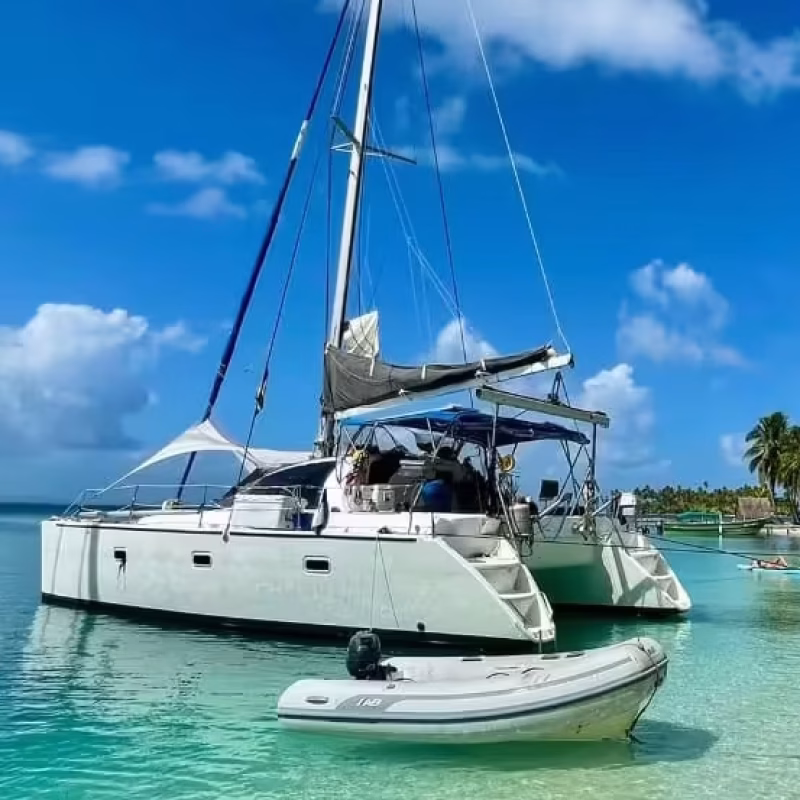 Lagoon 37 catamaran moored off a sandy beach lined with palm trees in San Blas, Panama